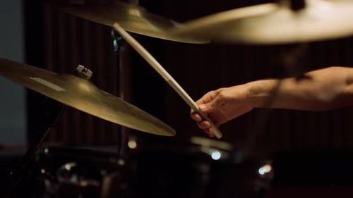 Manos de un hombre de cerca tocando un instrumento de percusión en un estudio de grabación.