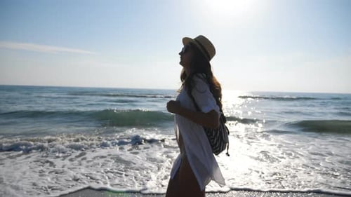Young Female Hiker in Beachwear Walking Along Ocean Coast. Attractive Woman with Backpack Strolling