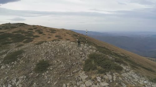 Young Man with Green Jacket Actively Resting During Trip Enjoying Freedom at Hill Top.