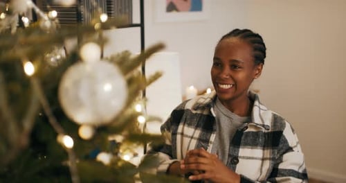 Woman Decorating Christmas Tree with Baubles at Home