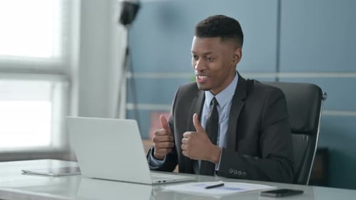 African Businessman Talking on Video Call on Laptop in Office