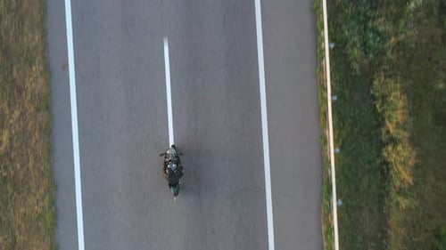 Top View to Motorcyclist Races His Motorcycle on Highway at Sunny Day