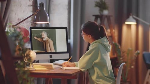 Mädchen schaut sich Schulunterricht am Computer an, während sie zu Hause studiert