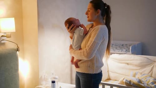Young Woman Holds Newborn Baby in Bedroom