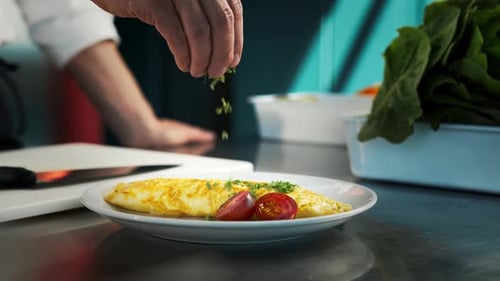 Professionelle Küche des Restaurants, Nahaufnahme: Der Küchenchef streut das fertige Omelett