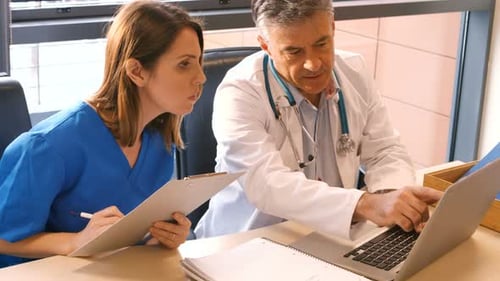 Doctor and Nurse Collaborating at Desk with Laptop