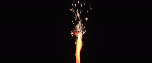 Red flame and sparks coming out of a firework in slow motion.