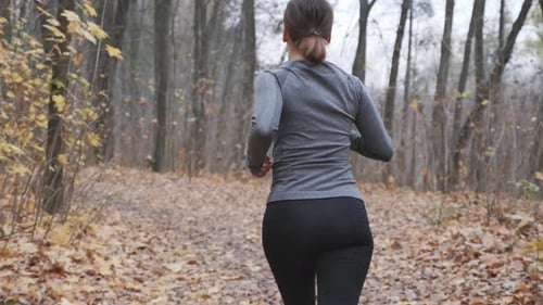 Woman losing weight through everyday running workouts in the park before work. Running concept
