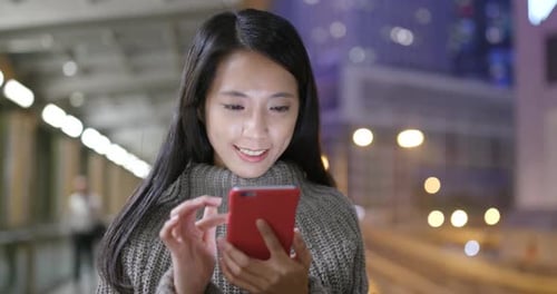 Young woman use of mobile phone in city at night