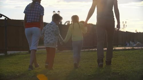 Family Walking Together at Sunset in Suburban Park
