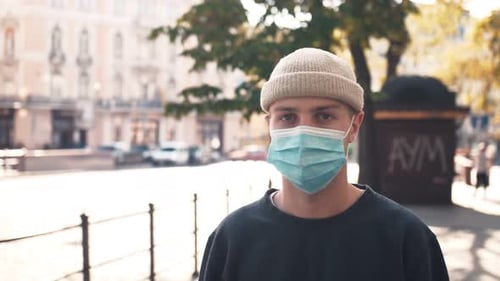 Young Caucasian Man Walking on Street City Center Wearing Virus Mask Face Protection in Prevention