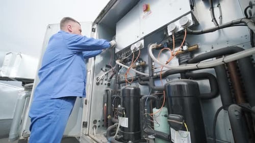 Repairman repairs electrical equipment in industrial setting