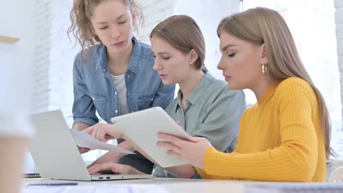 Young Creative Women Working on Laptop with Documents and Tablet