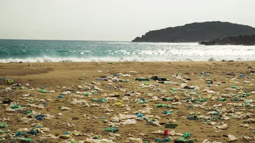 A beach densely polluted with plastic garbage. Powerful waves break on the coast