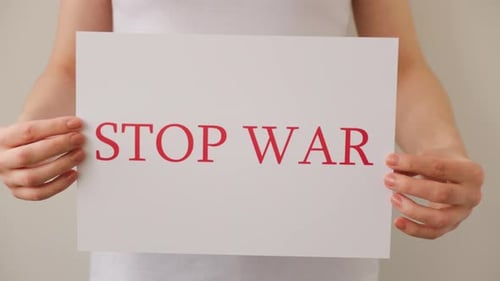 Close Up of a Protester Hands Holding Cardboard Banner with the Words No War
