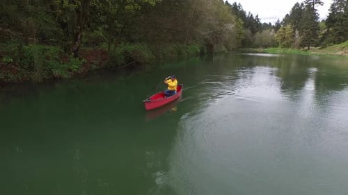 Aerial shot of man paddling canoe in lake