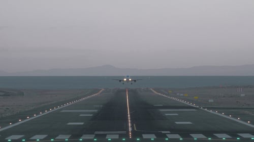 Airplane Landing on Runway at Dusk by Ocean