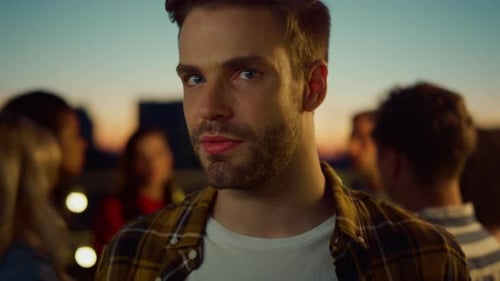 Man Smiling at Party on Rooftop at Sunset