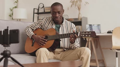 Man Plays Guitar for Smartphone Recording at Home