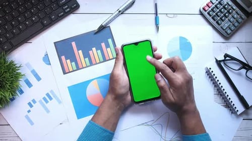 Using Smart Phone with Green Screen and Financial Charts on Table