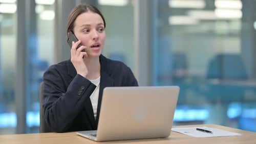 Professional Woman Talking on Smartphone at Office Desk