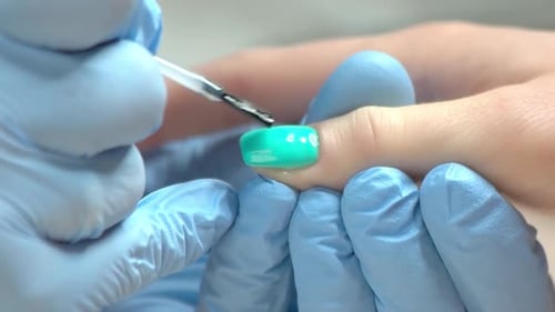 Applying Teal Nail Polish with Gloved Hands