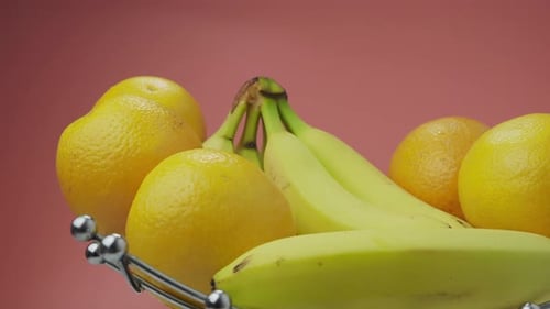Bananes et oranges sur fond rose