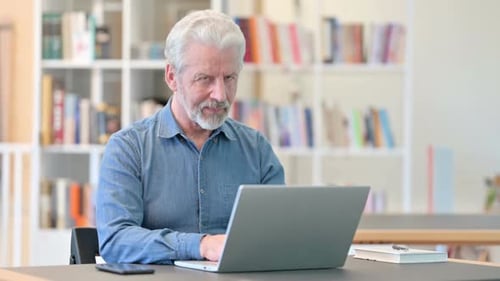 Adult with gray hair types on laptop