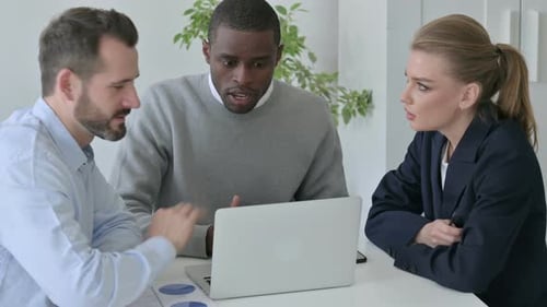 Male and Female Business People Arguing While Using Laptop in Office