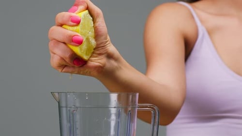 Woman Squeezing Lemon into Water Pitcher