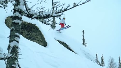 Skier Jumps Over Snowy Rock in Winter Landscape