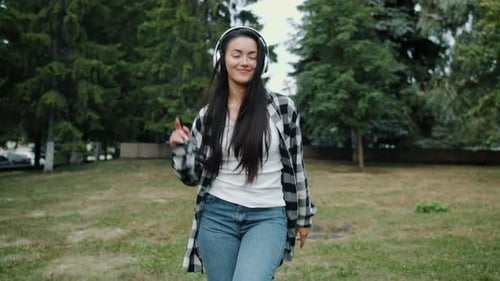 Slow Motion of Young Asian Lady in Headphones Dancing in Urban Park Alone