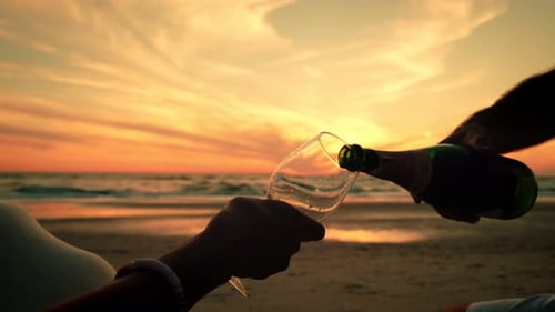 Close Up View of Couple Takes Two Glasses in Their Hands with Wine Against the Sunset at the Sea