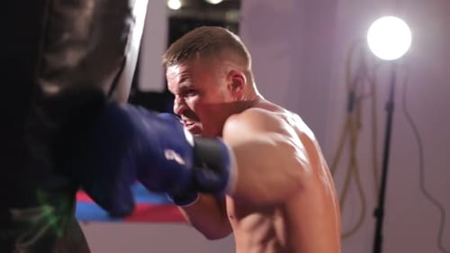 Intense Man Punching Bag in a Gym, Close Up