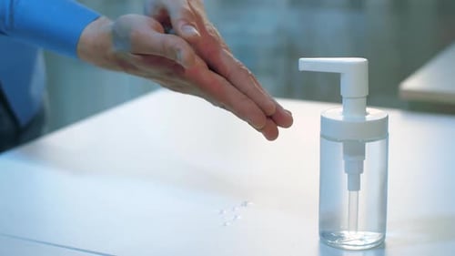 Hands Sanitizing with Clear Liquid on Table