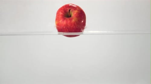 Super Slow Motion One Red Apple Falls Under the Water with Splashes and Air Bubbles