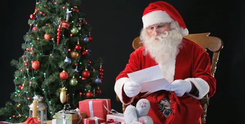 Santa Claus Reading Letter at Christmas Table