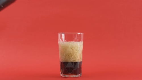 Dark Soda Being Poured Into Glass with Ice