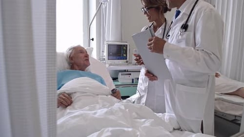 Doctors Consulting with Elderly Patient in Hospital Room