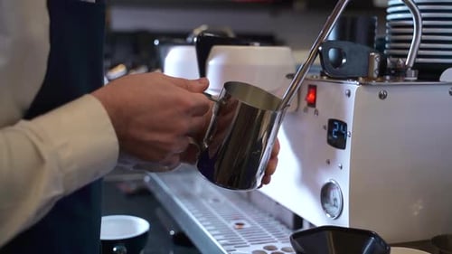 Barista Holding Pitcher at Espresso Machine