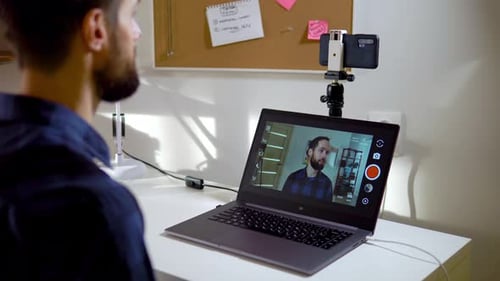 Man Records Himself on Video on a Smartphone Via a Computer