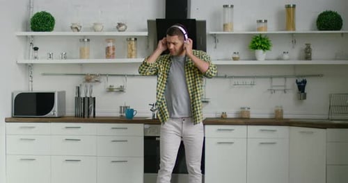Young Man Dancing with Headphones in Modern Kitchen