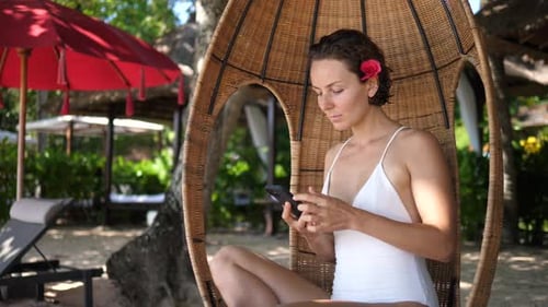 Woman Relaxing on Beach Using Mobile Phone