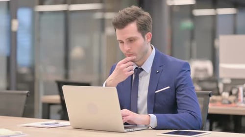 Businessman Thinking While Working on Laptop in Office