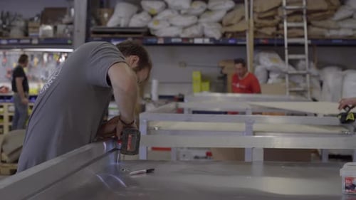 Three workers fabricate mobile pizza ovens