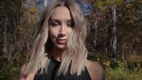 Smiling Woman with Blonde Hair in Autumn Forest