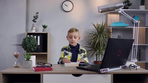 Child Reading a Book at Desk Indoors