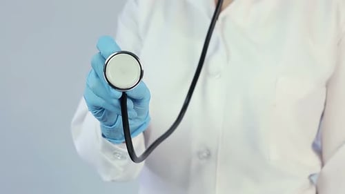 Doctor in Lab Coat and Medical Gloves Holding Out Stethoscope to Camera, Clinic