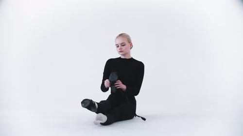 Young Dancer Putting On Black Ballet Shoes