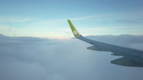 Airplane Wing over Fluffy Clouds in Sky